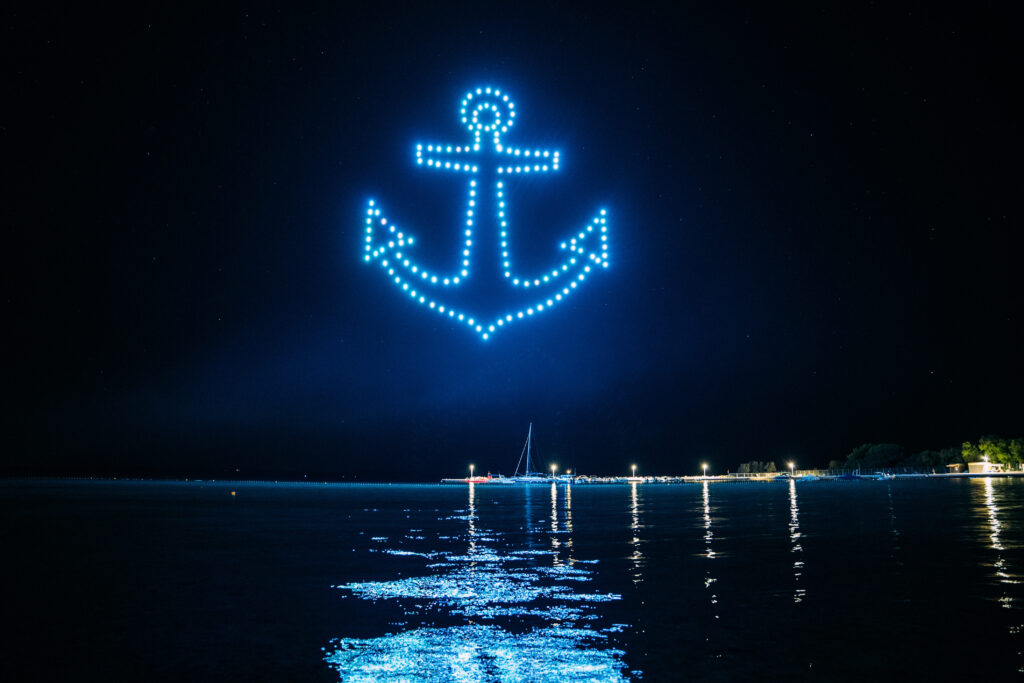 Skydance Drone Light Shows anchor drone formation above sea with glowing lights at night