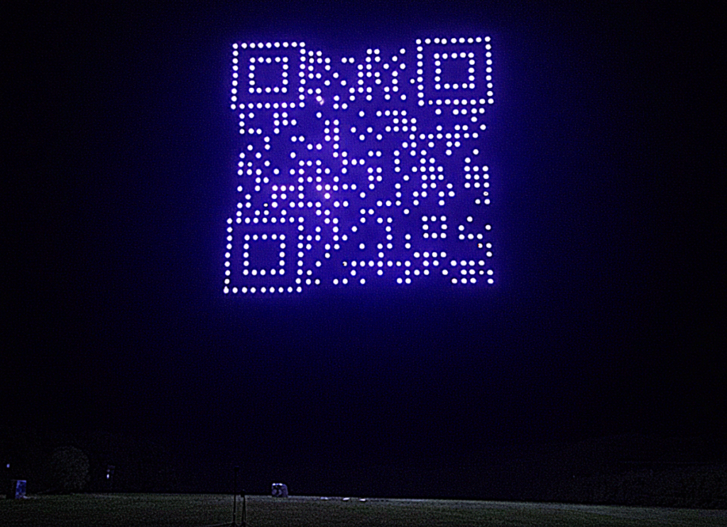 Skydance Drone Light Shows QR code drone formation glowing in night sky above field