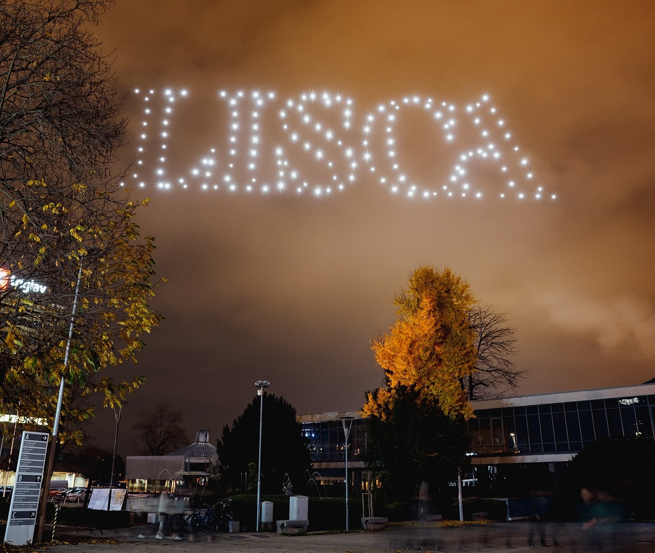 Skydance Drone Light Shows forming the word LISCA in the night sky above a city