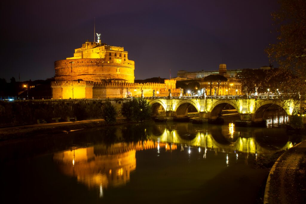 A stunning night view of Castel Sant'Angelo and its reflection over the Tiber River in Rome, Italy.